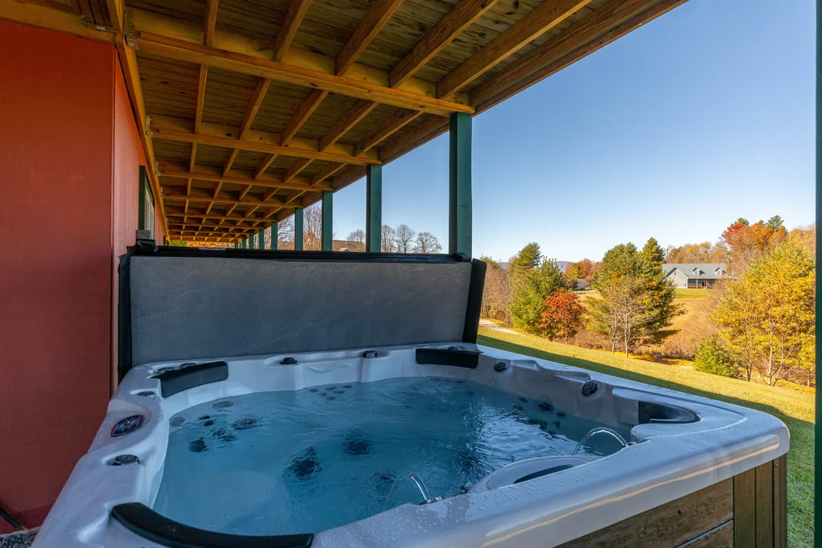 This image displays a brand new hot tub nestled on the deck, surrounded by the scenic mountain landscape. The wooden structure of the deck offers an inviting space while the hot tub itself looks ready for relaxation, with clear views of the outdoors.